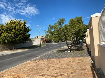 an empty street with trees on the side of a road at Blouberg Cosy 2 bedroom house in Cape Town