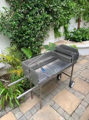 a barbecue grill sitting on a sidewalk next to a bush at Petite France:luxury thatched 4BRcottage with pool in Franschhoek