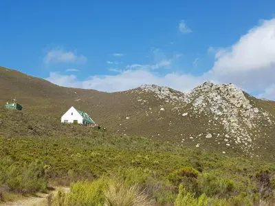 a white house on the side of a mountain at Witteklip self-catering farm in Kleinmond