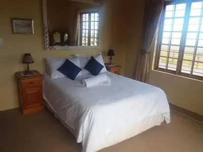 a bedroom with a large white bed with blue pillows at Witteklip self-catering farm in Kleinmond