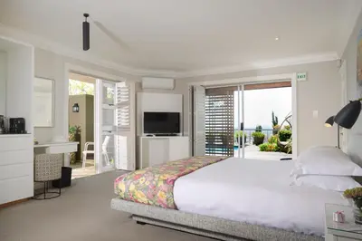 a white bedroom with a bed and a television at Fijnbos Private Manor in Gordonʼs Bay