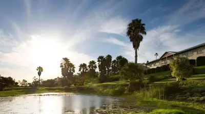 a golf course with a pond and palm trees at The Caledon Hotel and Spa in Caledon