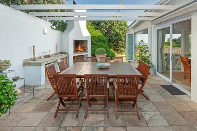 a patio with a wooden table and chairs and a fireplace at Wild Waters at Kraal Rock on the cliffs in Hermanus in Hermanus