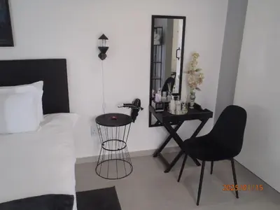 a bedroom with a bed and a chair and a mirror at Mi Amor Accommodation in Brackenfell