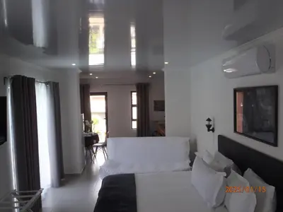 a white bedroom with a bed and a living room at Mi Amor Accommodation in Brackenfell