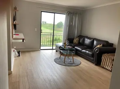 a living room with a black leather couch and a glass table at Mini Suits in Cape Town