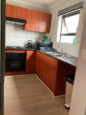 a kitchen with wooden cabinets and a sink at Mini Suits in Cape Town