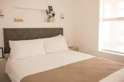 a bedroom with a bed with white sheets and a window at Hermanus Sea Breeze in Hermanus