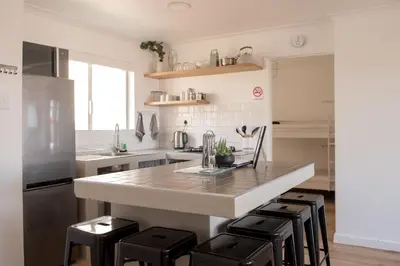 a kitchen with a large island with black stools at Hermanus Sea Breeze in Hermanus