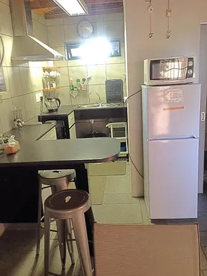 a kitchen with a white refrigerator and a table and stool at Aan de weg in Cape Town