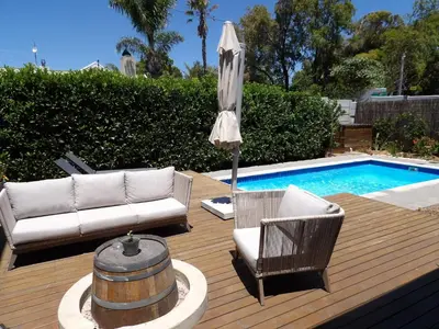 a patio with a couch and an umbrella next to a pool at Maîté Iphupho in Somerset West