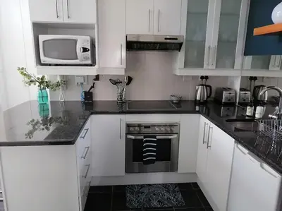 a kitchen with white cabinets and a stove and a microwave at The Lookout Loft, a short stroll into town in Stellenbosch
