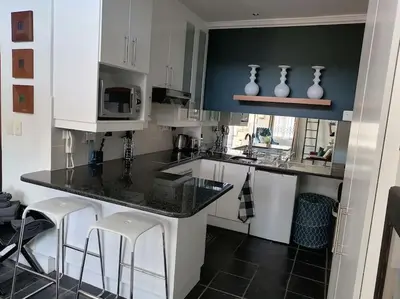 a kitchen with white cabinets and a black counter top at The Lookout Loft, a short stroll into town in Stellenbosch