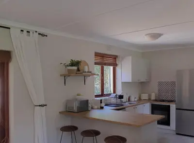 a kitchen with a counter and some stools in it at Three Streams Cottages in Franschhoek