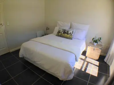 a bedroom with a large bed with white sheets and pillows at The Rondebosch on Belmont in Cape Town