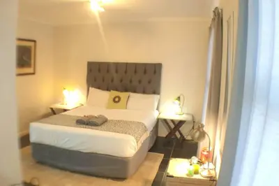 a bedroom with a large bed and two lamps at The Rondebosch on Belmont in Cape Town