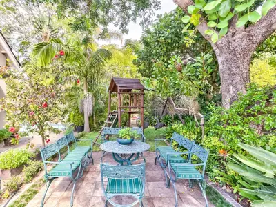a patio with chairs and a table and a tree at Villa Jesdene in Cape Town