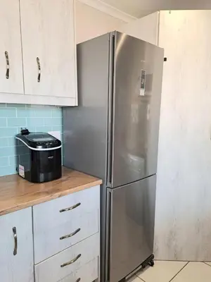 a stainless steel refrigerator in a kitchen with white cabinets at Cosy and Central Family Home in Cape Town