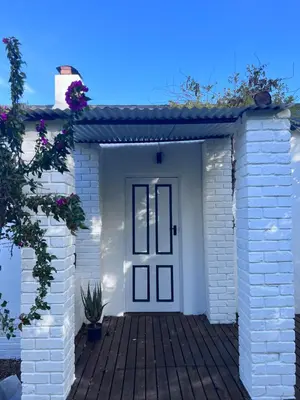 a white brick house with a black door at Tollbosch in Somerset West