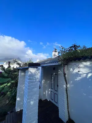 a small white building with the ocean in the background at Tollbosch in Somerset West