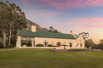 a white house with a mountain in the background at Southwinds Estate in Hermanus