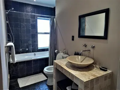 a bathroom with a sink and a toilet and a tub at Mandalay Beach Guest House in Bloubergstrand