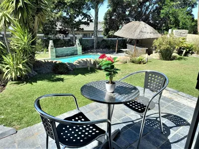a table with two chairs and a table with a flower at Mandalay Beach Guest House in Bloubergstrand