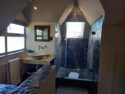 a bathroom with a shower and a sink at Mandalay Beach Guest House in Bloubergstrand