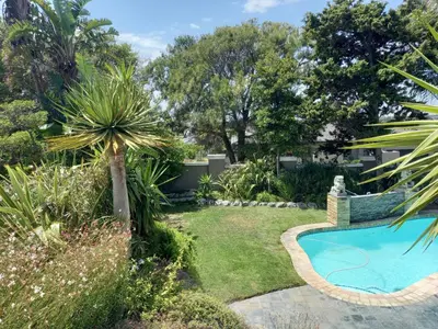 a garden with a swimming pool and plants at Mandalay Beach Guest House in Bloubergstrand