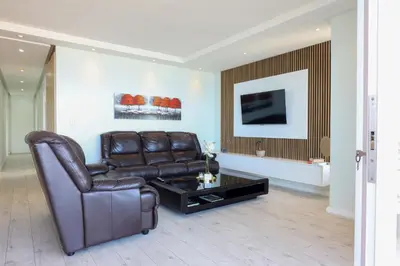 a living room with a leather couch and a coffee table at Portico 1006 Beachfront Apartment with Panoramic Views in Cape Town