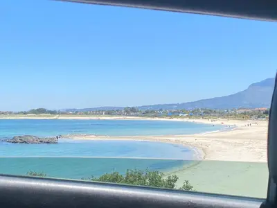 a view of a beach from a car window at Shalom On The Bay in Cape Town