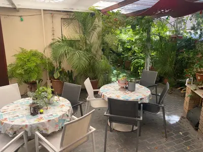 a patio with two tables and chairs and plants at Shalom On The Bay in Cape Town