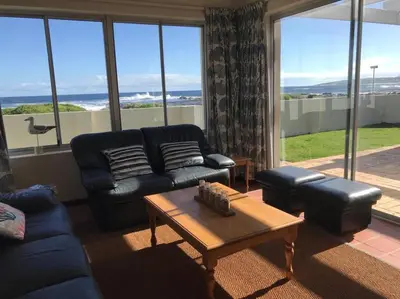 a living room with a couch and a coffee table at La Mer, a beautiful beachfront home in Sandbaai in Hermanus