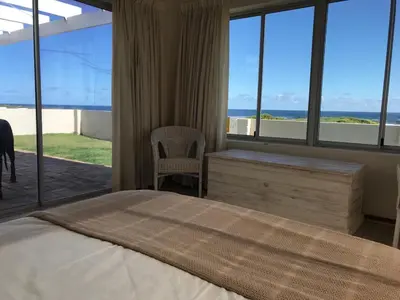 a bedroom with a bed and a view of the ocean at La Mer, a beautiful beachfront home in Sandbaai in Hermanus