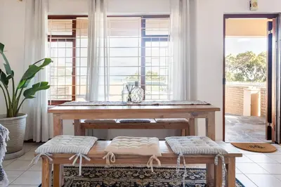 a living room with a table and a window at Innie Baai Beach House in Cape Town