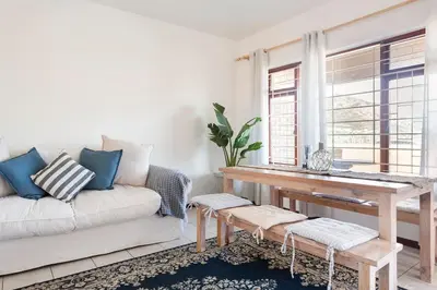 a living room with a couch and a table at Innie Baai Beach House in Cape Town