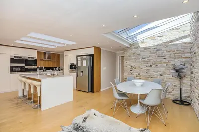 a kitchen and dining room with a table and a stone wall at The Island Beach Villa in Cape Town