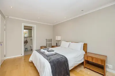 a white bedroom with a bed and a table at The Island Beach Villa in Cape Town