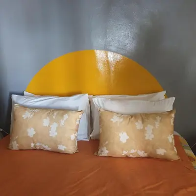 a bed with a yellow headboard and two pillows at Irma's farmstay at the Nuy Valley Guesthouse in Nuy