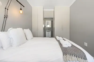a bedroom with a white bed with white pillows at Cape on Porterfield 5 in Bloubergstrand