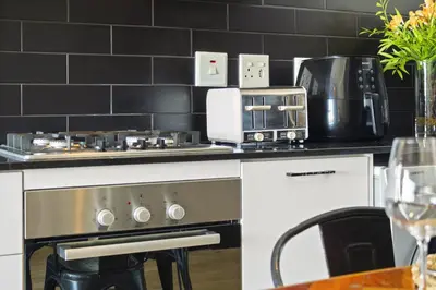a kitchen with a stove top oven next to a table at Cape on Porterfield 5 in Bloubergstrand