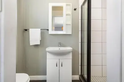 a white bathroom with a sink and a mirror at Cape on Porterfield 5 in Bloubergstrand