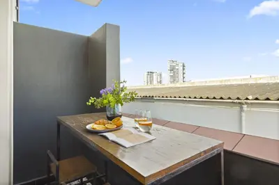a table with a glass of wine and a plate of food on a balcony at Cape on Porterfield 5 in Bloubergstrand
