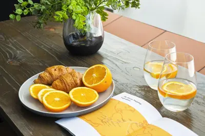 a plate of oranges on a table with wine glasses at Cape on Porterfield 5 in Bloubergstrand