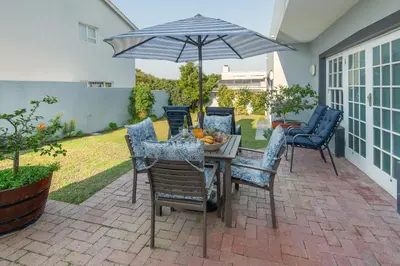 a table and chairs with an umbrella on a patio at 3-Bed-Mountain View in Hermanus