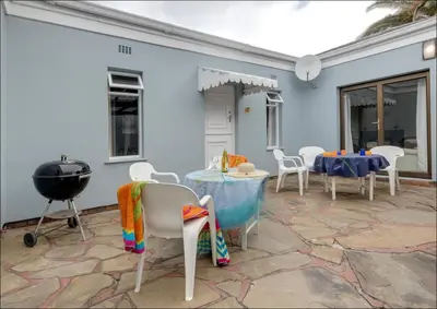 a patio with a table and chairs and a grill at Island Time in Hermanus