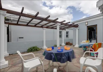a patio with a table and chairs and a pergola at Island Time in Hermanus