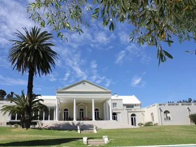 a white building with a palm tree in front of it at Retreat at Waterfall Valley in Paarl