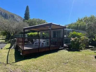 a house with a deck with a table and chairs at Great spot with a view in Hermanus , South Africa in Hermanus