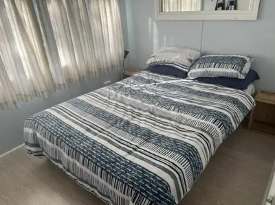 a bed with a striped comforter in a bedroom at Great spot with a view in Hermanus , South Africa in Hermanus